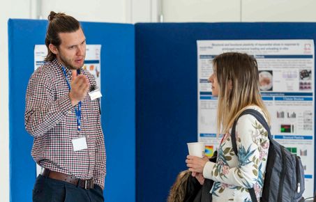 Man and woman talking in front of poster display
