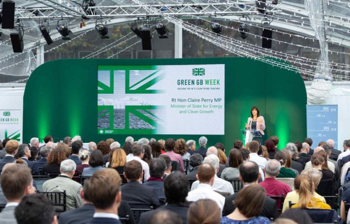 Claire Perry standing on a stage next to Green GB week branding with an audience in front