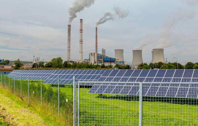 solar panels with coal and nuclear plant in background