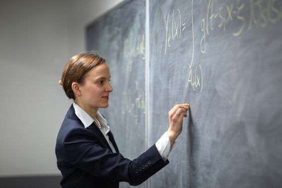 Maths student writes on a blackboard