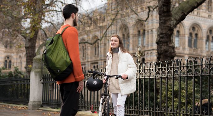 Student with a bike talking to another student outside the Natural History Museum
