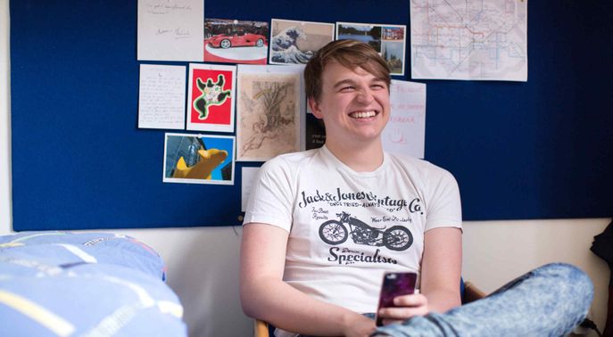 Student laughing in halls of residence room