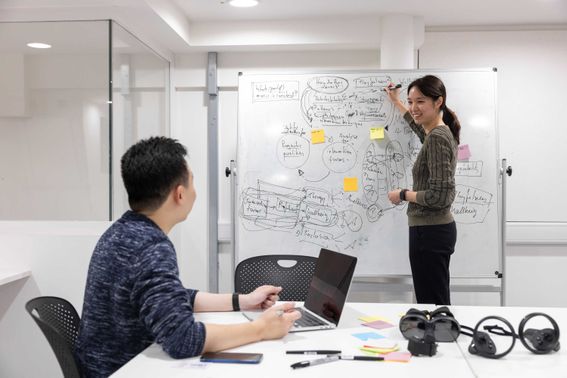 Two students in a room writing on a whiteboard