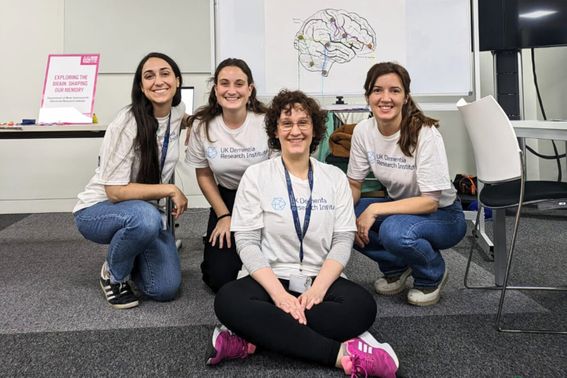 Four UK DRI researchers pose in front of whiteboard with diagram of the brain on it at the festival