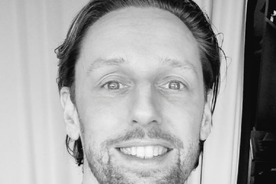 a black and white close up head shot of a smiling man