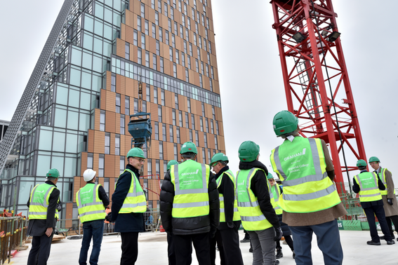 Construction workers looking up at a tall building with a crane in the background