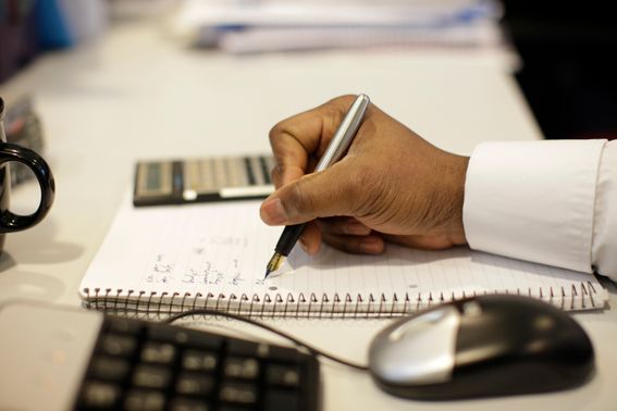 hand with mouse and calculator writing on pad