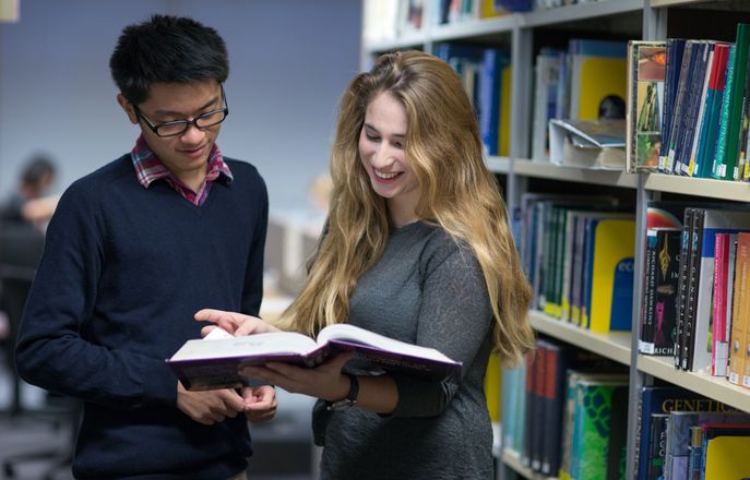 Students standing with book in hand