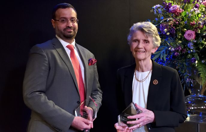 Harris Bokhari and Angela Vincent on stage holding their Distinguished Alumni Awards