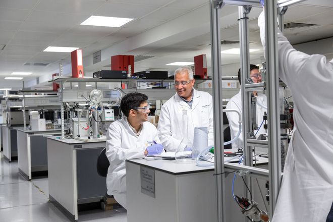 A student working at a lab bench talks to a member of staff
