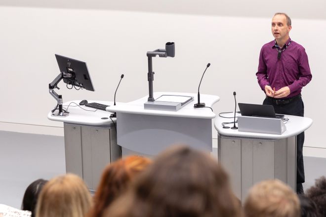 An academic presenting from behind a lectern