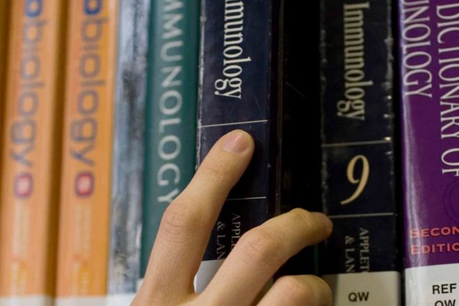 A picture of a hand taking a library book from a shelf