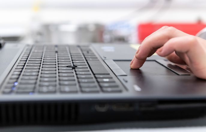 Hand resting on a laptop keyboard 