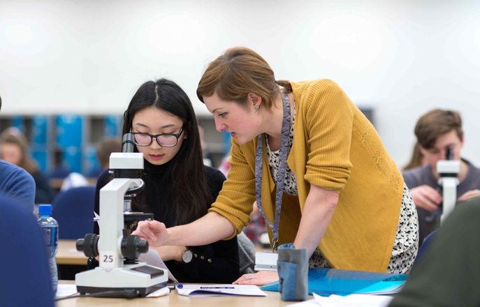 Lecturer and student examining materials with a microscope