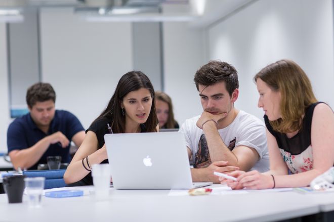 students discuss around a laptop