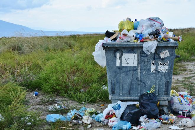 An overflowing rubbish skip at the edge of a beach