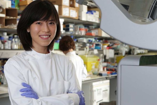 A student in a laboratory smiling and looking at the camera