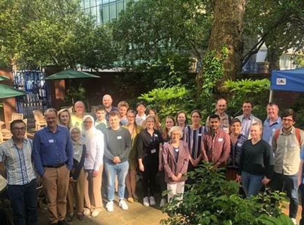 A photograph taken outside of 25 people standing in a group and looking at the camera