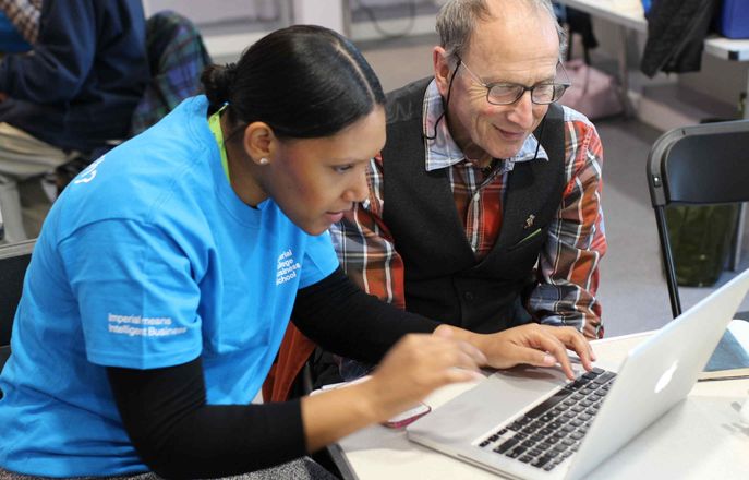 An Imperial student helps an elderly local White City resident to use their laptop