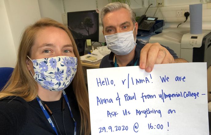 Researchers Anna and Paul holding a sig promoting the Reddit AMA.