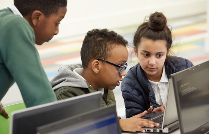 school children gathered around laptop