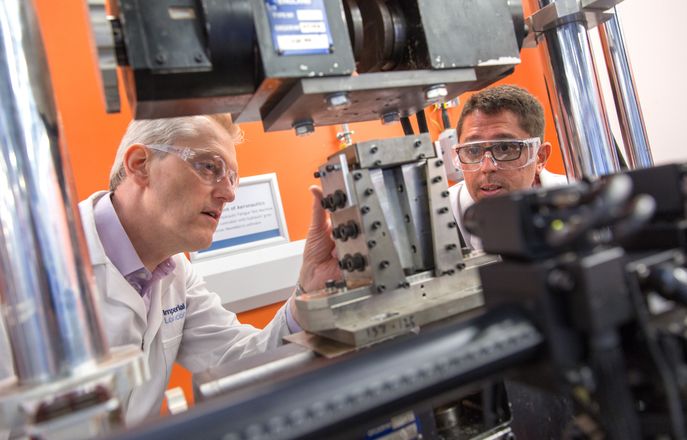 An image of two people looking at a manufacturing machine