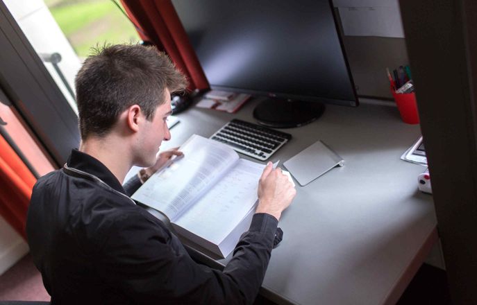Student reading a textbook in his room