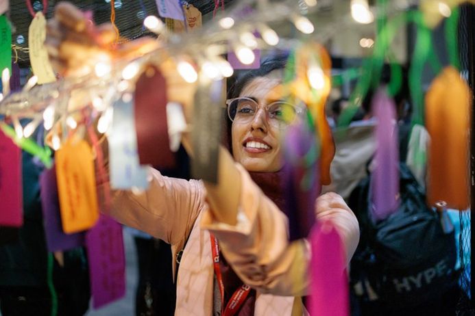 Woman hangs a tag on a tree in the Creative Science Zone