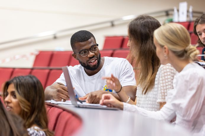 A man and two women sitting in a lecture theatre and having a discussion