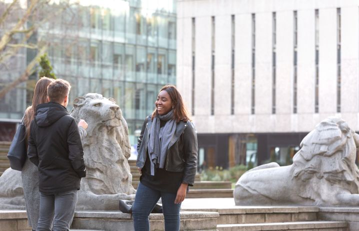 Students chatting by the lion statues on campus.