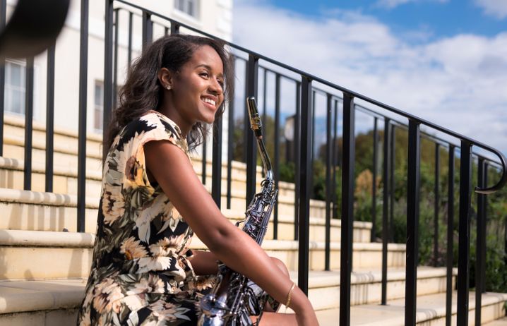 Gabrielle Grey sitting on outside steps holding a saxophone