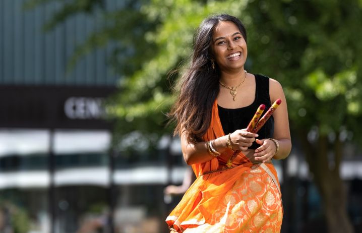 Nandini Bhudia in traditional orange dress in front of Imperial's central library