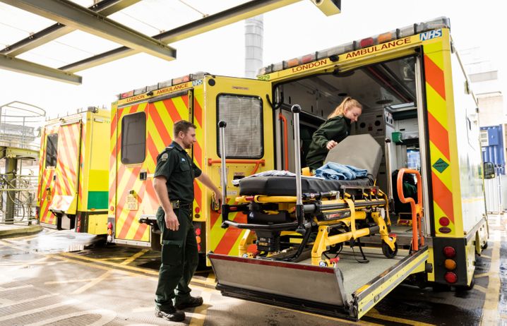 Two paramedics loading a bed on to an ambulance