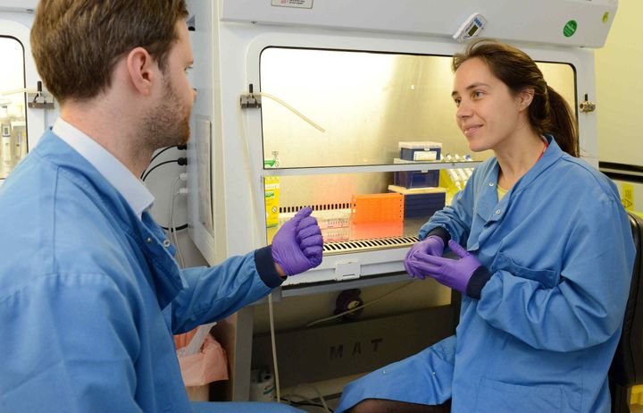 Two researchers chat in front of hoods