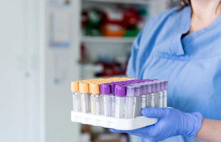 A clinical researcher wearing protective equipment and holding test tubes