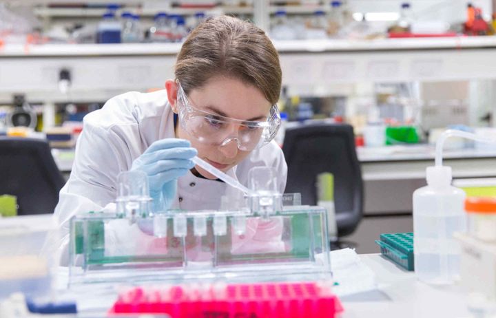 A PhD student using a pipette in a lab