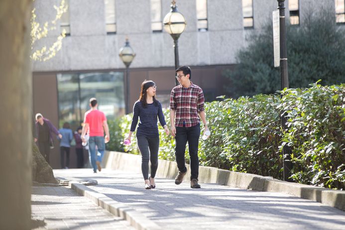 Two students chat as they walk across the Dangoor Plaza at the South Kensington Campus