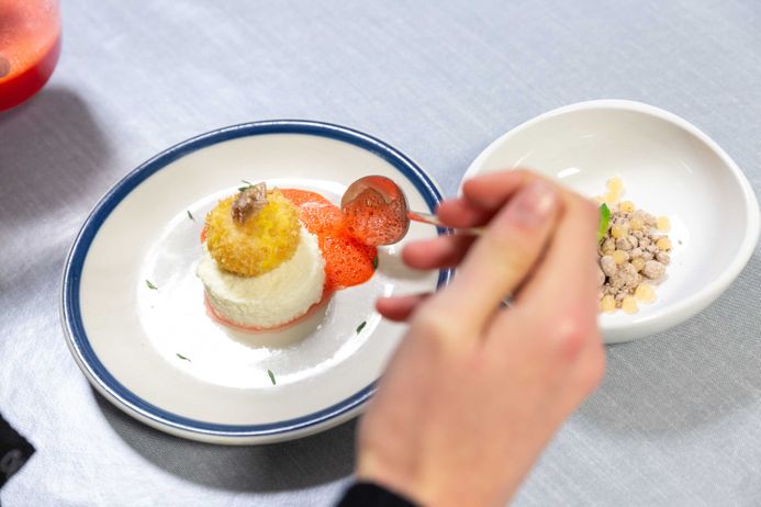 Fancy food dish being dressed by a hand