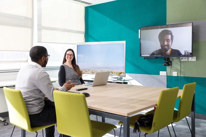 Colleagues smiling and talking in a hybrid meeting
