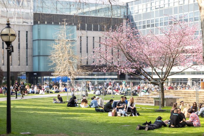 Students sitting on the Queen's lawn in spring