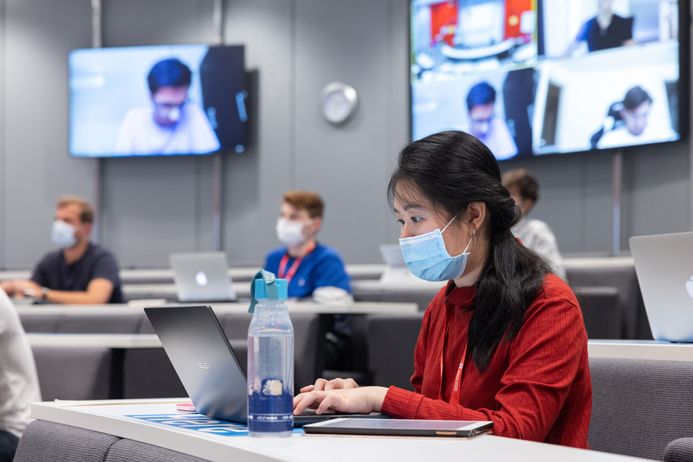 Students wearing face masks attend a lecture in the Business School while others attend remotely during the COVID-19 pandemic