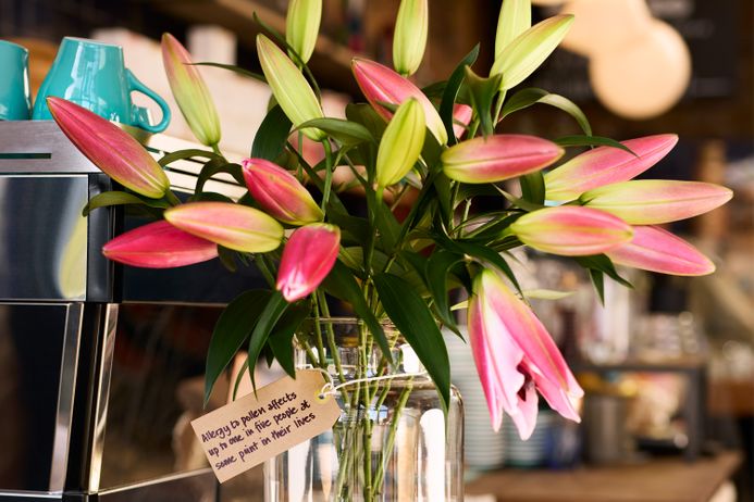 A vase of flowers with a label stating 'Eye-watering stats: allergy to pollen affects up to one in five people at some point in their lives, while the NHS estimates that there are more than 10 million people with hay fever in England'
