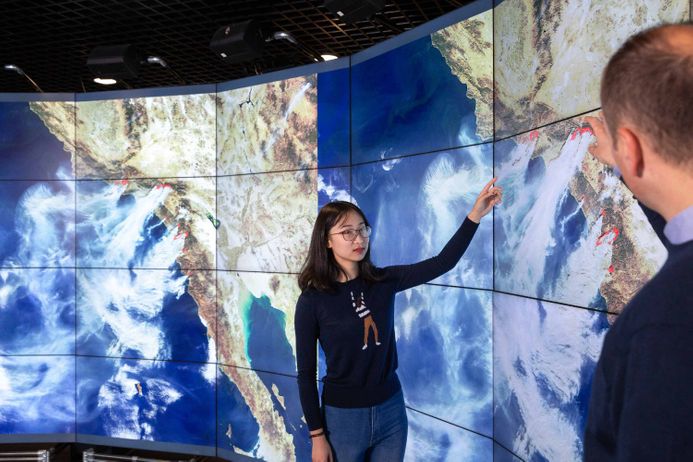 A student pointing at the earth as visualised on a data screen