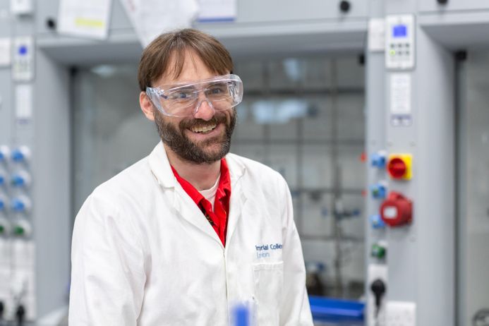 Jason Hallett in a lab wearing a lab coat and goggles