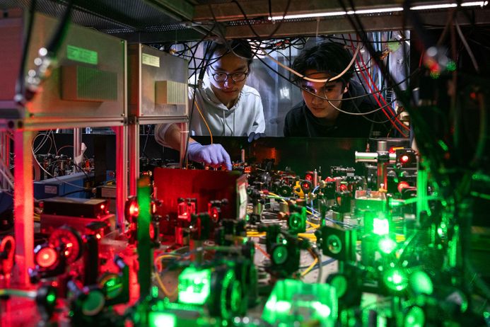 Two Imperial scientists examine lasers on an optical table