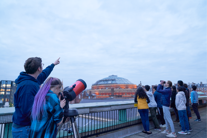 Members of the Astronomy society look through a telescope towards the sky above the Royal Albert Hall