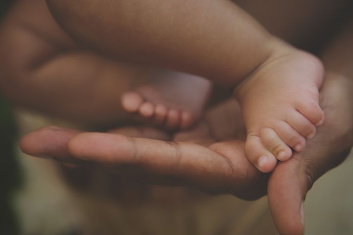 A picture of a new born baby's feet being held in the hands of an adult