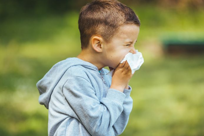 A picture of a child blowing his nose into a tissue