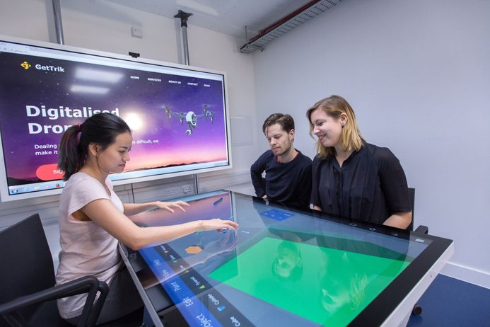 Three students use an interactive table in the Enterprise Lab