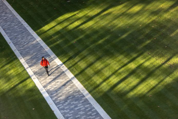 A student walks across the Dangoor Plaza on the South Kensington Campus
